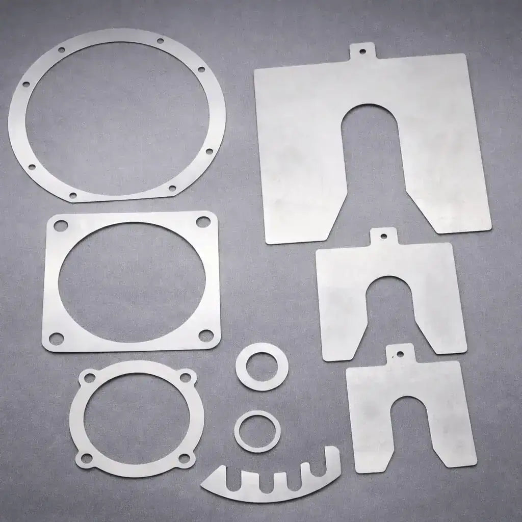 Custom laser cut metal shims in circular, slotted, and square profiles for industrial alignment and gap adjustment.